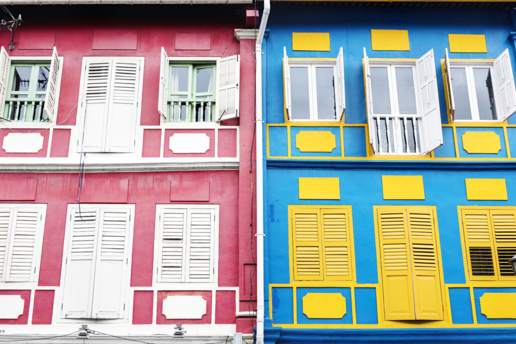 Colorful heritage shophouses in Singapore with contrasting red and blue facades, symbolizing diverse property types for valuation comparison.