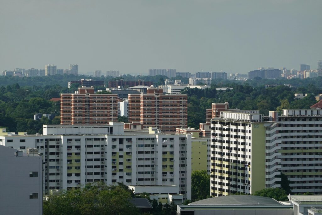 View of HDB residential blocks surrounded by greenery in Singapore with a city skyline in the background.