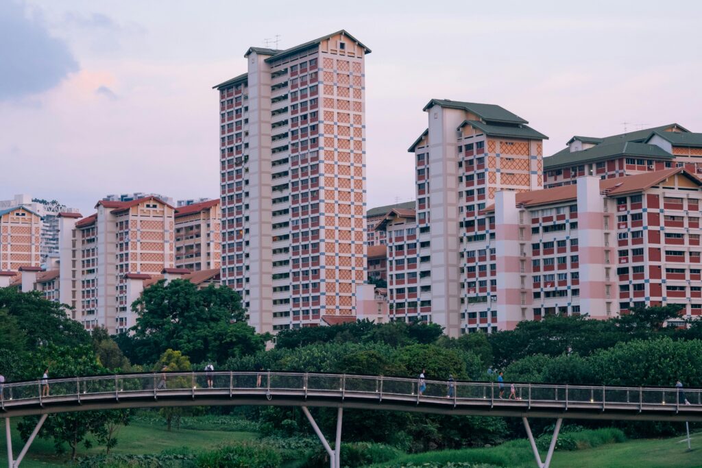 Residential HDB flats in Singapore with a pedestrian bridge in the foreground during dusk.