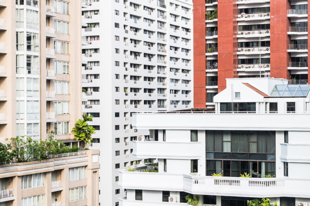 High-rise HDB and private apartment buildings in Singapore with visible balconies, air-conditioning units, and rooftop greenery